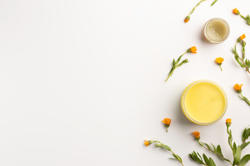 Organic cosmetic concept. Flowers of calendula and jar of skin care cream, isolated on white background. Flat lay, top view, copy space.