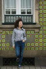 A mixed-race woman in front of houses in Porto, Portugal.