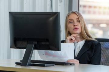 Serious caucasian businesswoman working on a computer at office desk, She looks confident and charming. Concept of equality in careers, talented women