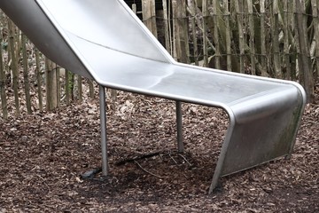 Metal slide with a wooden fence in the background