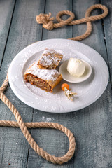 Apple strudel with caramel and nuts in icing sugar with a scoop of ice cream.