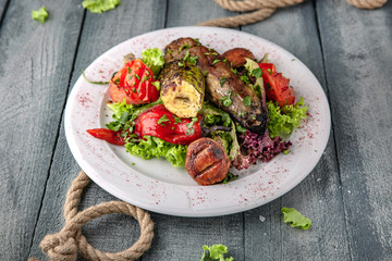 Hot grilled vegetable salad: zucchini, eggplant, tomato, pepper.  On a turquoise background. Sea mood concept menu.