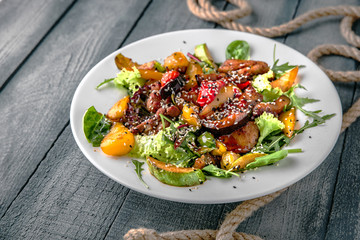 Warm salad of chicken or beef with grilled vegetables and sesame seeds in a sweet and sour sauce. On a turquoise background. Sea mood concept menu.