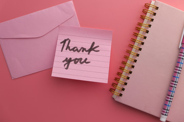 Close up of thank you note and envelope on pink background 