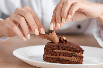 Female chef decorating tasty dessert in kitchen, closeup