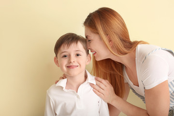 Happy little boy and his mother on color background