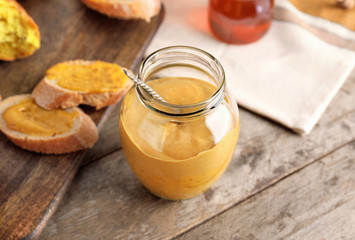 Jar of tasty honey mustard sauce on wooden table