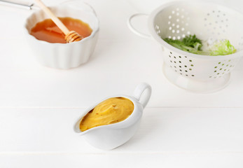 Gravy boat of tasty honey mustard sauce on white wooden table