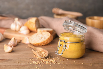 Jar of tasty honey mustard sauce on wooden table