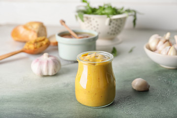 Jar of tasty honey mustard sauce on color background