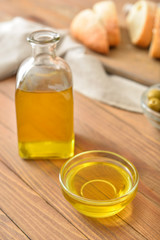 Bowl and bottle of tasty olive oil on wooden table