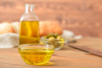 Fototapeta na wymiar Bowl of tasty olive oil on wooden table