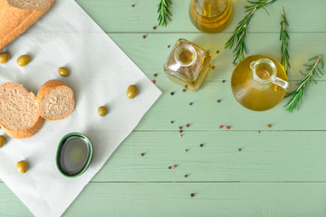 Tasty olive oil with bread and spices on wooden table