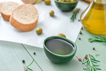 Bowl of tasty olive oil on wooden table
