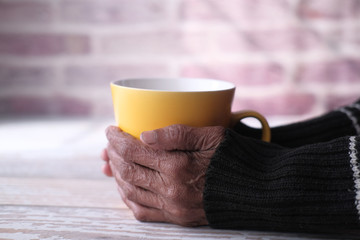 A senior woman holding a cup of coffee or tea in hands
