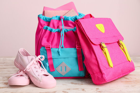 School Backpacks And Shoes On Table Against Color Background