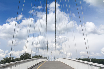 Obraz premium Pedestrian suspension bridge with a bicyle lane connecting the two sides of the Drava river in Osijek, Croatia, with the cables visible and the steel structure of the bridge
