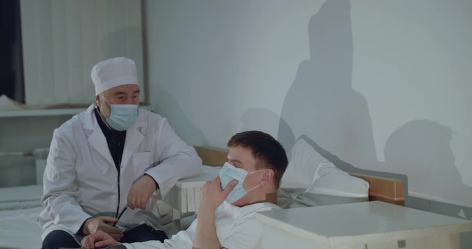The doctor takes care a sick patient, coughing on hospital bed