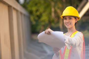 Woman Supervisor hard hat safety suit holding blueprint inspection building estate...
