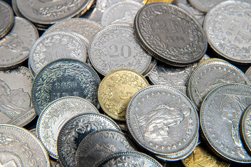 Multiple 1/2, 1, 2, 5 swiss coins franc, centimes CHF money isolated on dark background.