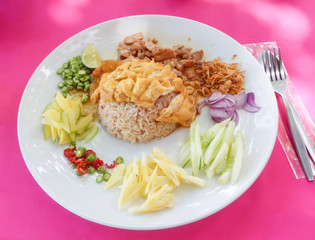 Set of rice with mas fried in batter on a white plate with slices of pineapple, onion, cucumber and pepper.