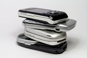 Stacked old mobile phones on white background