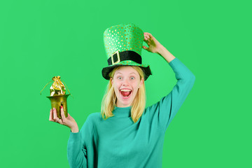 Saint Patrick's Day. Green top hat. Blonde girl in Leprechaun costume holds pot with gold....
