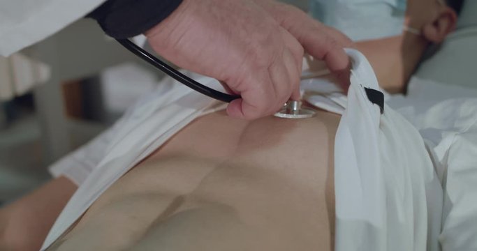 Listening to the sick boy's breath with phonendoscope on chest in hospital