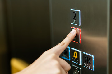 People pressing the button in the lift and select the first floor by using the forefinger. Elevator...