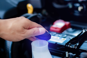 hand of a mechanic is checking the car windshield wiper cleaning spray water reservoir black bottle cap with clear and communicative pictogram sign symbol show the liquid function inside