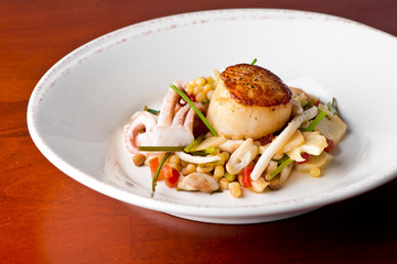 Scallops. Pan seared jumbo sea scallops, sauteed in garlic herb butter and plated with fresh vegetables and a reduction sauce. Classic French Bistro Dish.  Plated by a chef