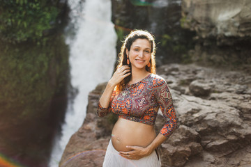 Portrait of young brazilian pregnant woman with naked belly. Happy and smile in harmony with nature. Maternity concept and pregnancy travel.