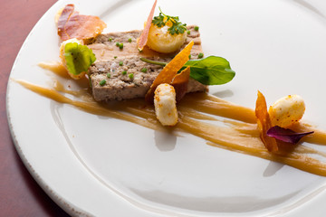 Duck Terrine. Traditional French cuisine a loaf of forcemeat or aspic, similar to a pâté, cooked in a covered pottery mold in a bain-marie.  Served at a French Bistro with potatoes and carrots