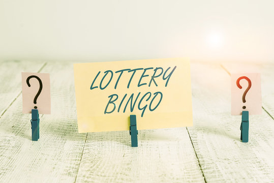 Conceptual hand writing showing Lottery Bingo. Concept meaning game of chance in which each player matches numbers printed Crumbling sheet with paper clips placed on the wooden table