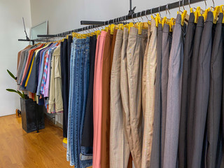 Pants and shirts hanging on shelf at clothing store