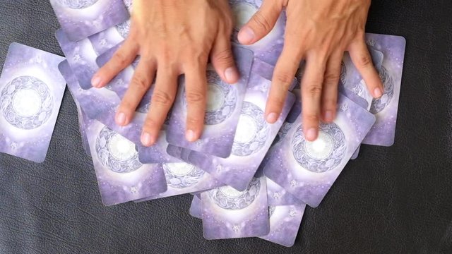 Close-up hands of fortune teller who shuffle Tarot cards for predict the fate and future next step, Divine magic and occultism concept, dark side concept, Top-view 