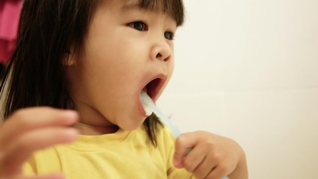 Happy little child girl brushing teeth and wash her face in the bathroom. Oral hygiene concept.