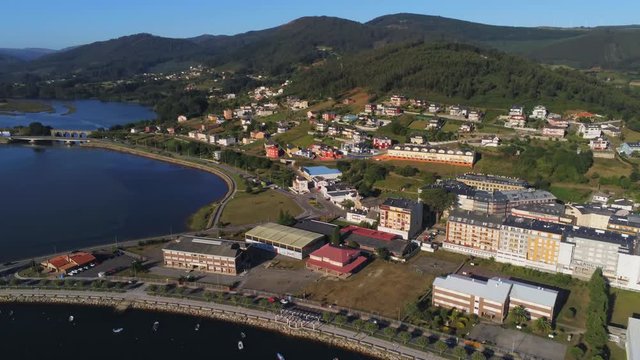 Aerial, pan, drone shot, of buildings, the town and the Ria de Viveiro river, on a sunny evening, in Lugo, Galicia, North Spain