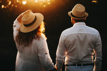 Caucasian man and his overweight charming wife wearing a white dress and hat are posing against the...