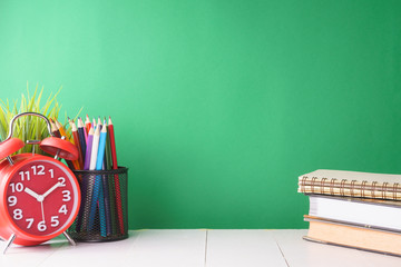 educational conceptual. books, alarm clock and stationery against green background. free copy space for your text
