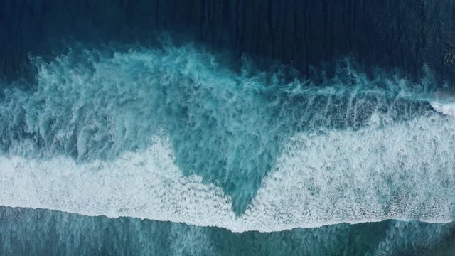 Slow-motion top down aerial view of the ocean giant waves, foaming and splashing