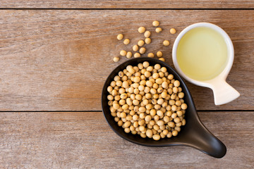 Soy bean oil with soybean seeds in   bowl isolated on rustic wood table background. Top view. Flat lay. 