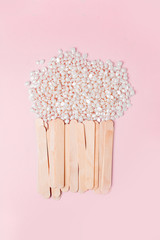 background texture wax for depilation of white pearl color on a pink background with wooden stick...