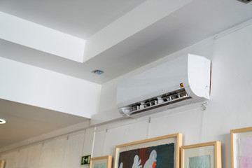 Air conditioning unit mounted high on wall near ceiling inside building