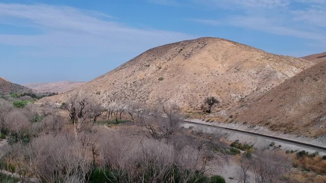 Drone footage from the Soledad canyon near los angeles, burnt trees and train track between mountains