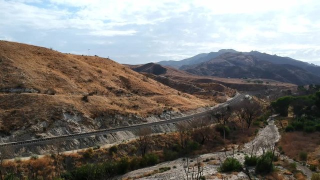 Flying in canyon in Los Angeles, Soledad. Train tracks in the mountains and burnt trees