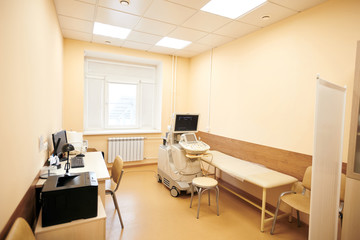 Interior of medical room with ultrasound machine, desktop computer, examination table and printer