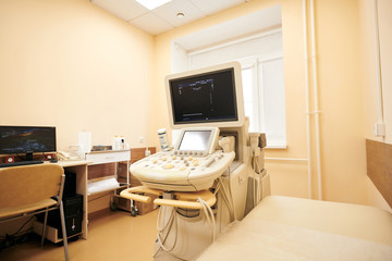 Modern ultrasound machine placed at examination couch in procedure room of clinic