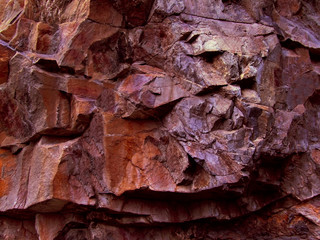 Brown red orange grunge background. Rock texture. Bright colorful stone background. Fragment of a mountain close-up.