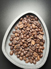 in a ceramic bowl, coffee beans on a black background.